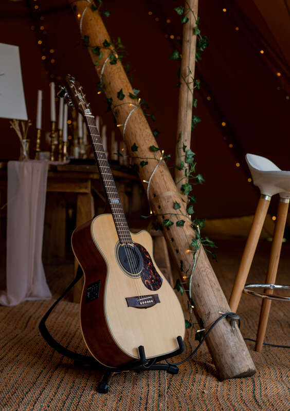 Acoustic guitar in a tipi next to beautifully decorated wooden tables