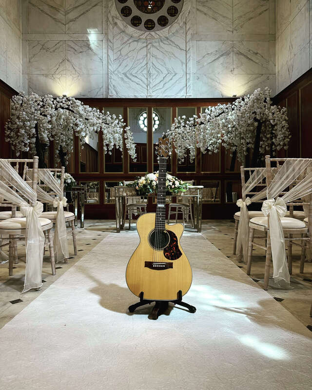 Acoustic guitar in a ceremony room with decorated walls and chairs