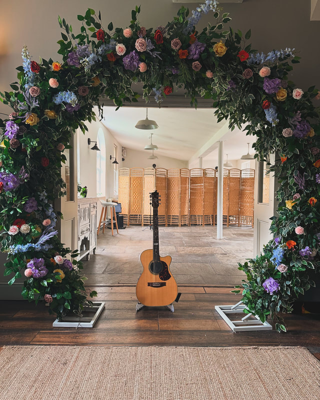 acoustic guitar under colourful flowers in ceremony room on wooden floor in kedleston country house