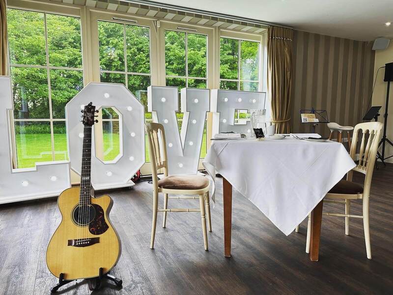 acoustic guitar at kelham house in a dining room next to table and chair with a love sign in the background
